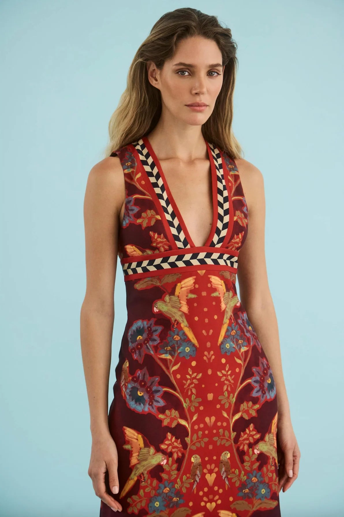 model wearing a print vneck sleeveless dress on a blue background 