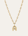 A gold chain necklace featuring a stylized lowercase 'a' pendant with a diamond accent, displayed against a light off-white background.