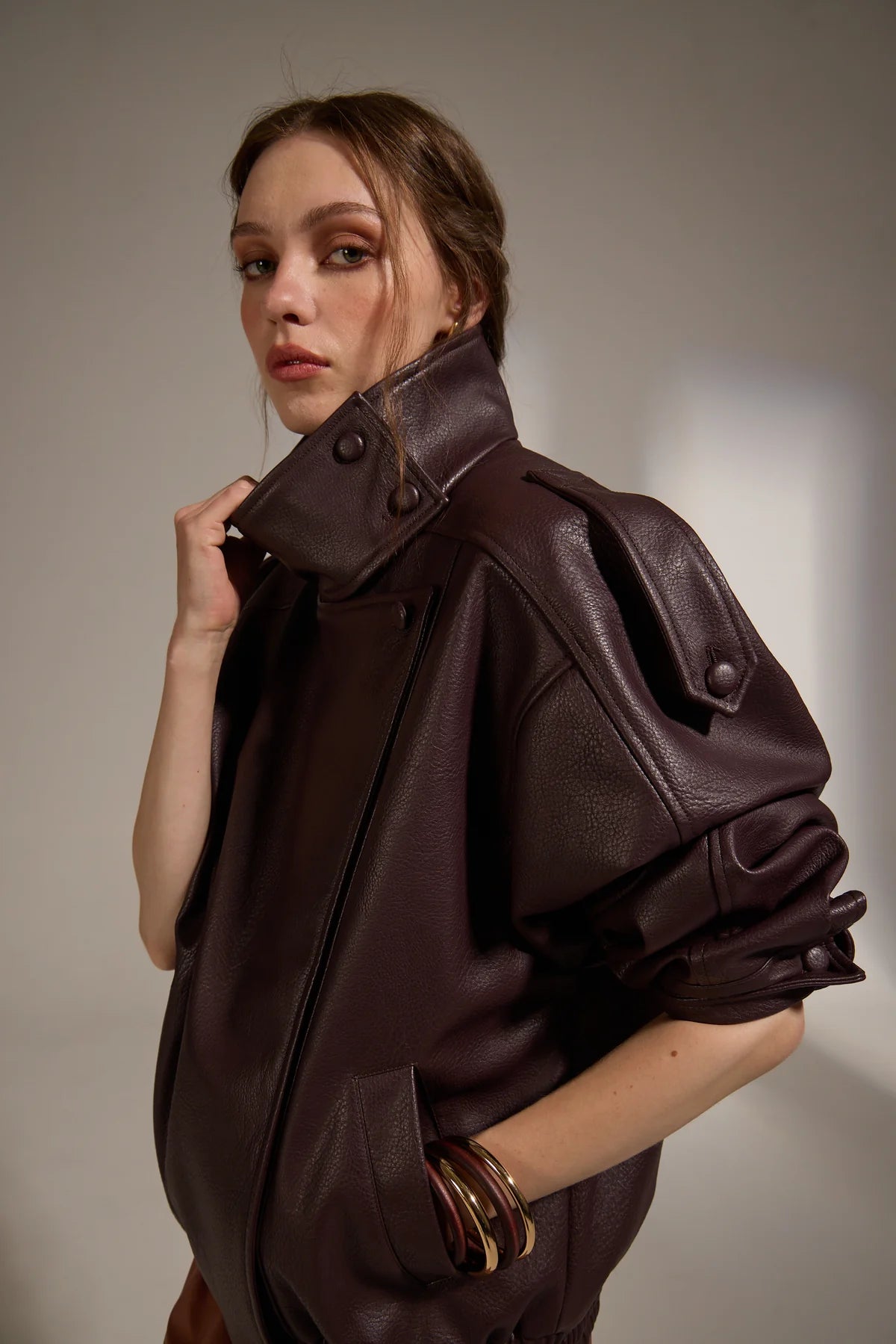 Woman wearing a brown leather jacket against a neutral background