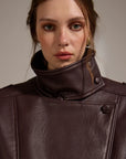 Close-up of a person wearing a brown leather coat against a neutral background