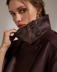 Woman wearing a brown leather coat with a neutral background