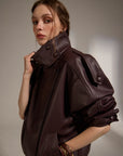 Woman wearing a brown leather jacket against a neutral background
