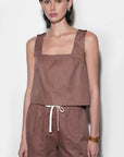 Woman wearing a brown sleeveless top and shorts against a white background