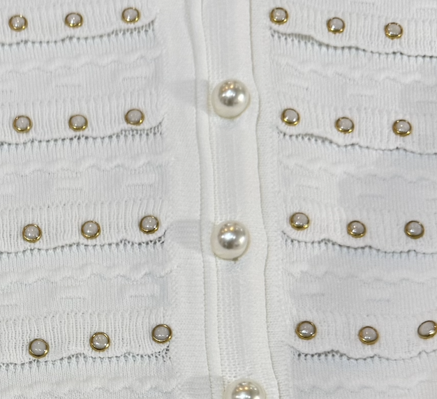 Close-up of a white textured fabric with pearl-like embellishments.
