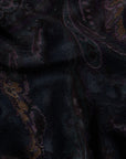 A close-up of a dark woven fabric with a subtle paisley pattern in black, deep purple, and muted gold.