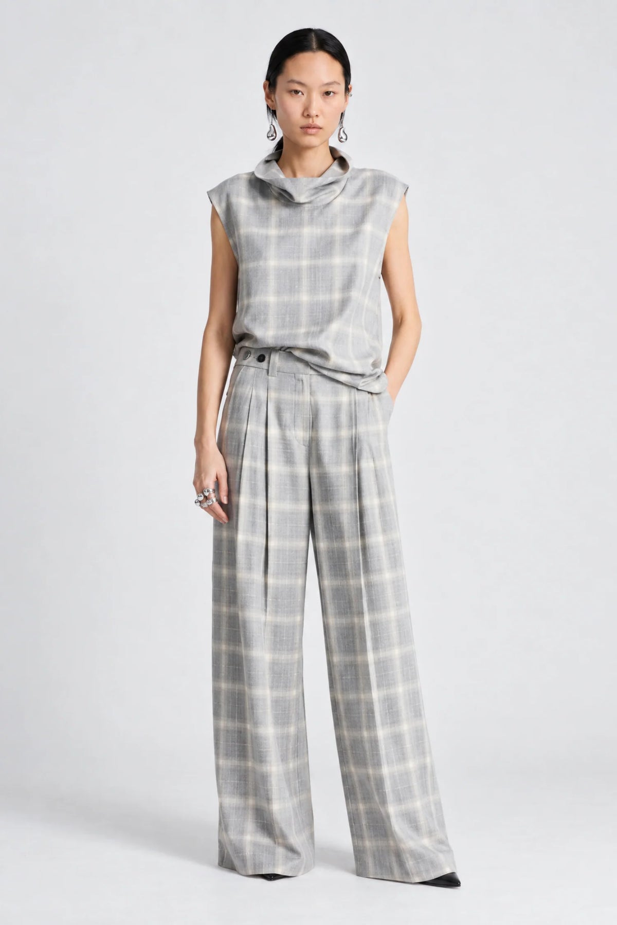 model wearing a grey and white plaid pant with a matching cowl neck sleeveless top 
