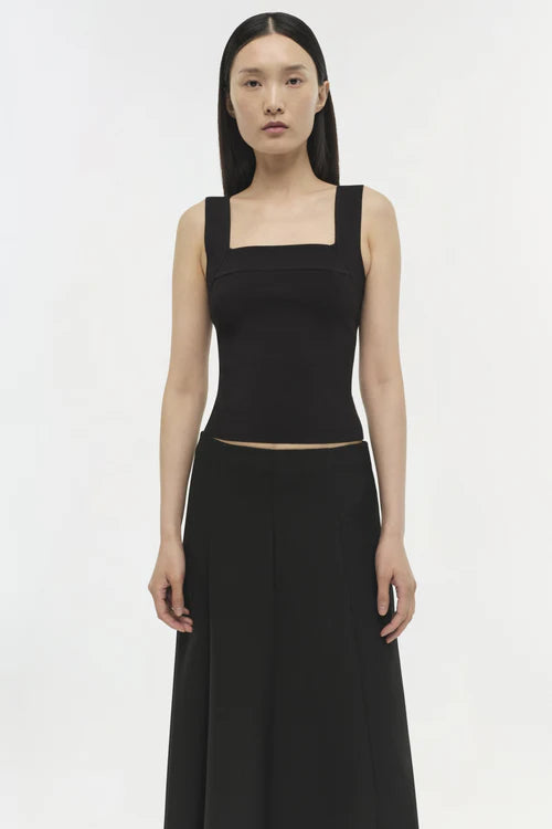 Woman wearing a black sleeveless top and long black skirt on a white background