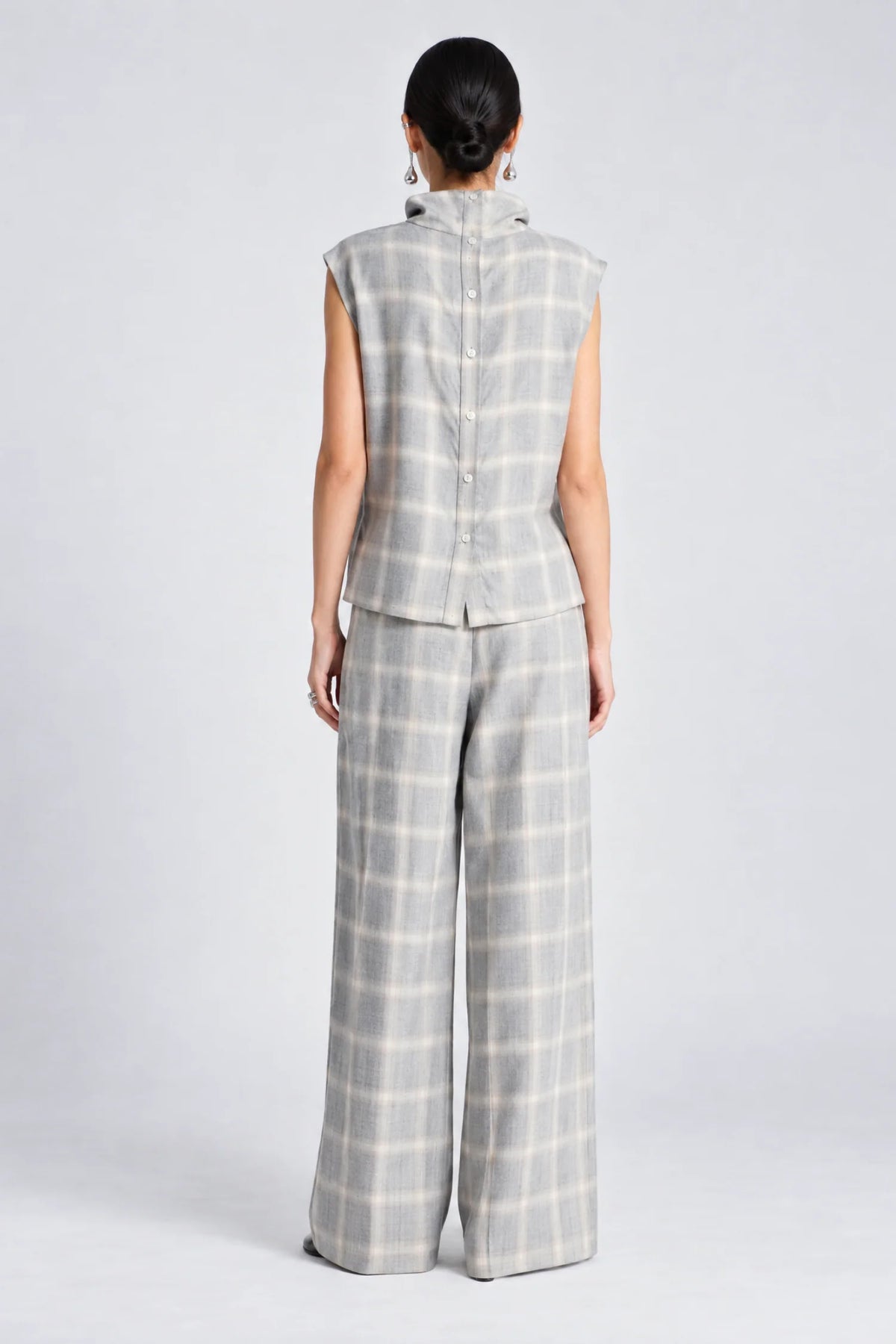 model wearing a grey and white plaid pant with a matching cowl neck sleeveless top, back view