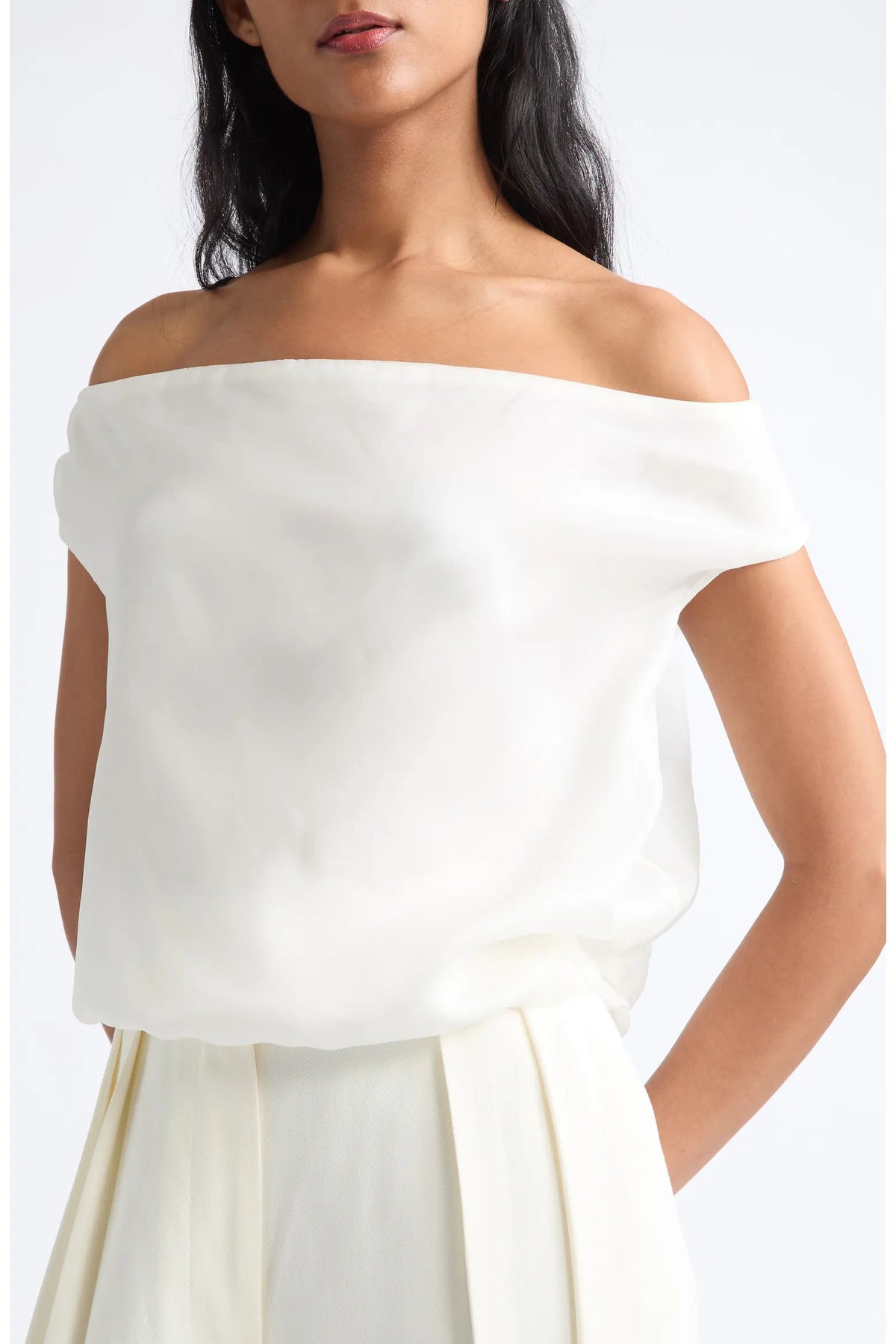 An off-the-shoulder white blouse with a soft, draped fabric and short cap sleeves, shown on a model against a plain white background.