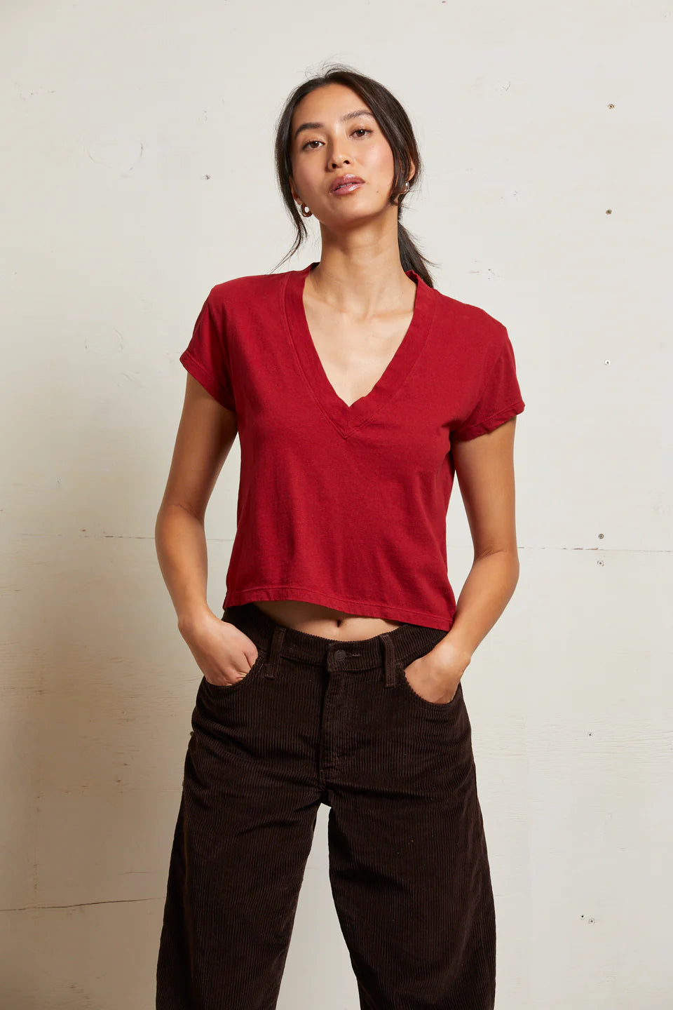 Person wearing a red top and dark pants against a plain background front view