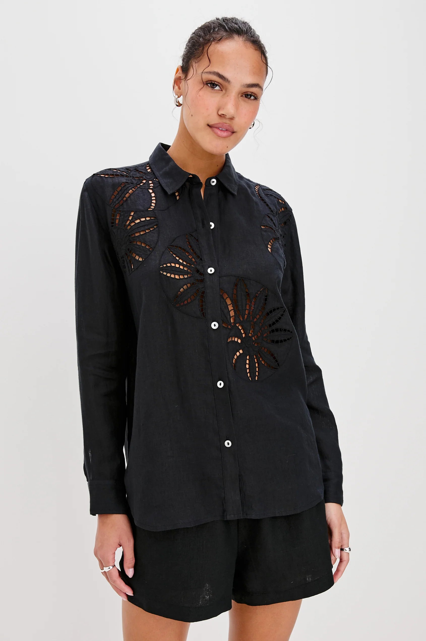 Woman wearing a black embroidered shirt and shorts on a white background front view