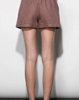 Person wearing brown shorts on a plain background