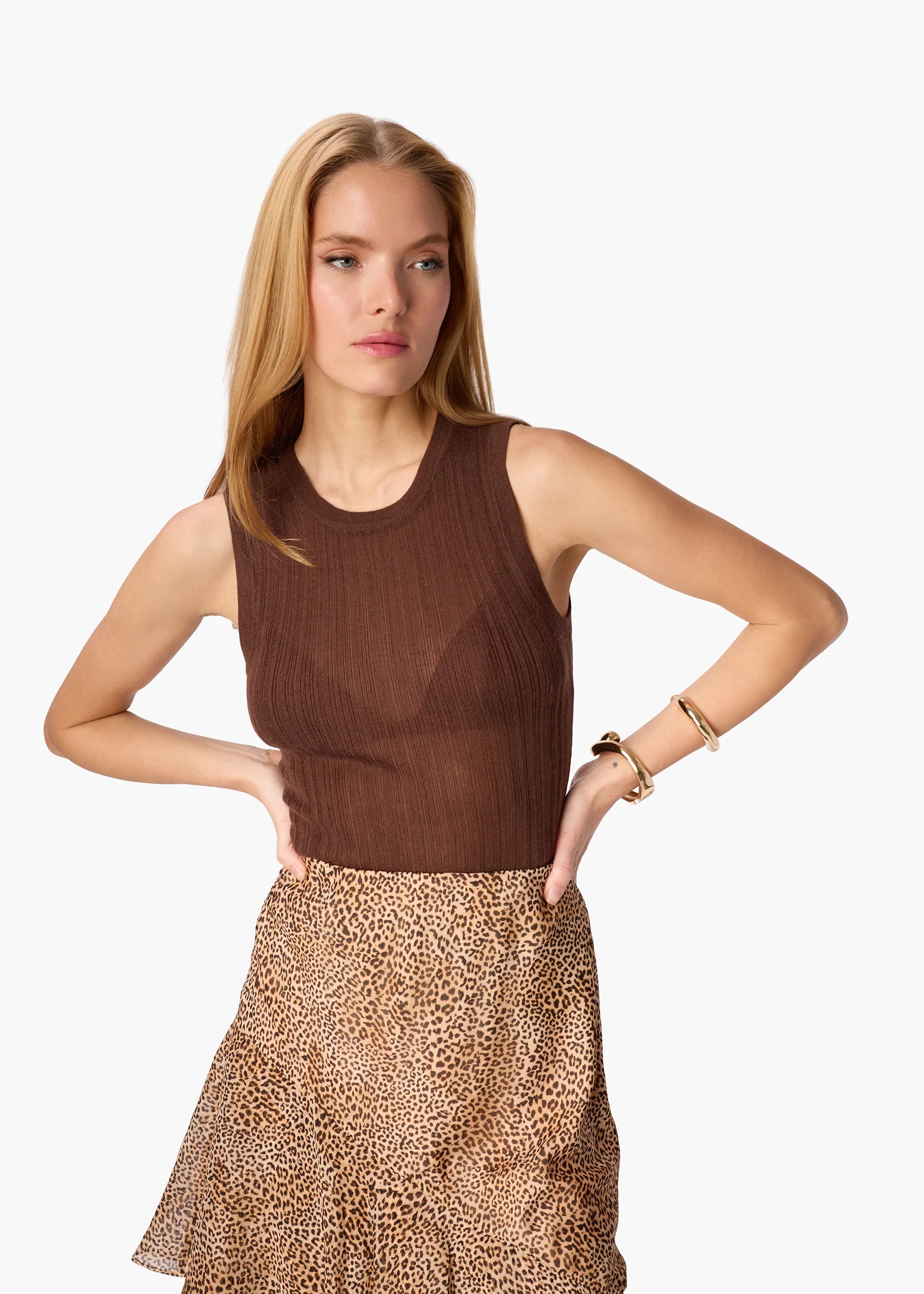 Woman wearing a brown sleeveless top and leopard print skirt on a white background