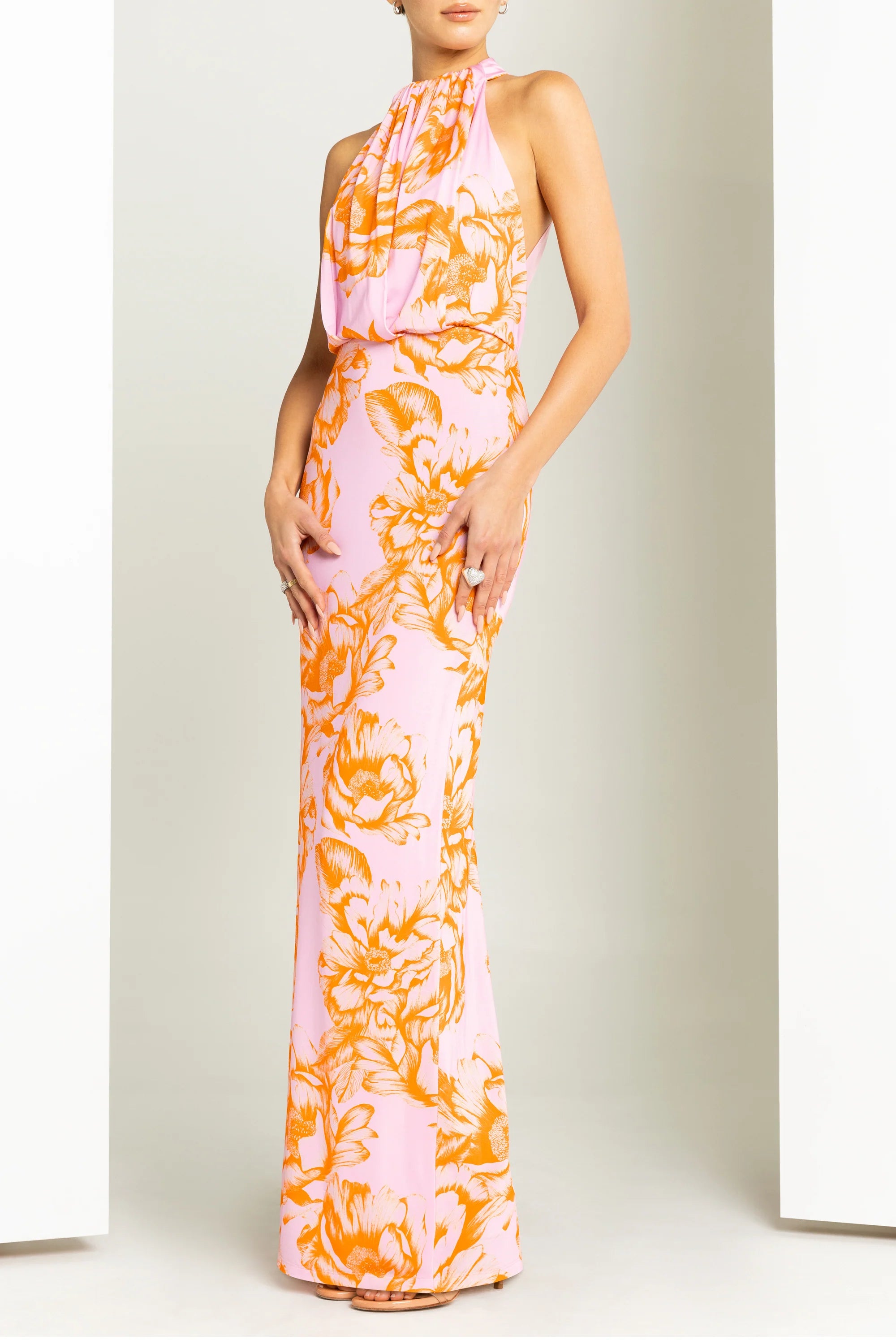 Woman wearing a pink and orange floral dress against a plain background