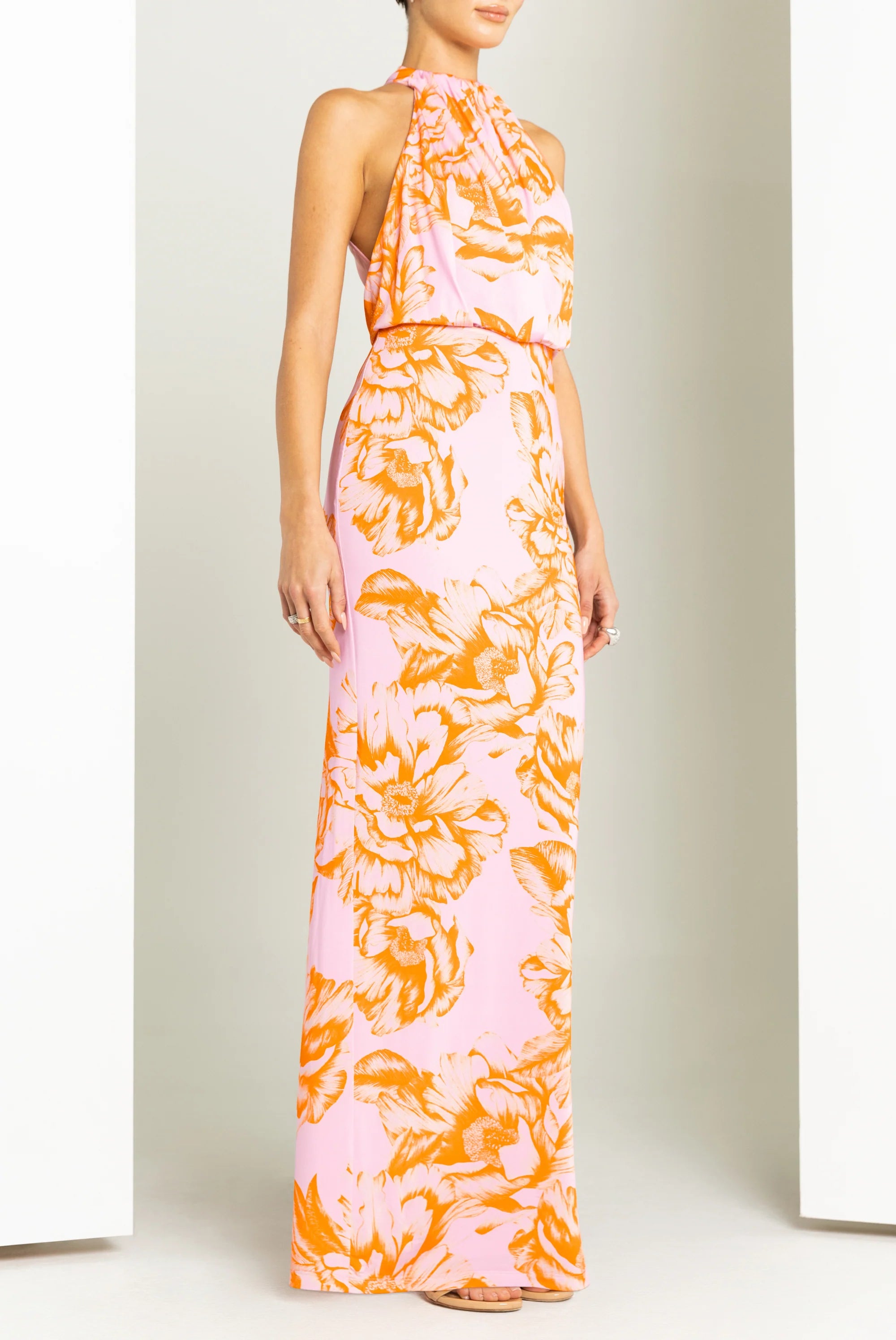 Woman wearing a floral dress with pink and orange pattern on a white background