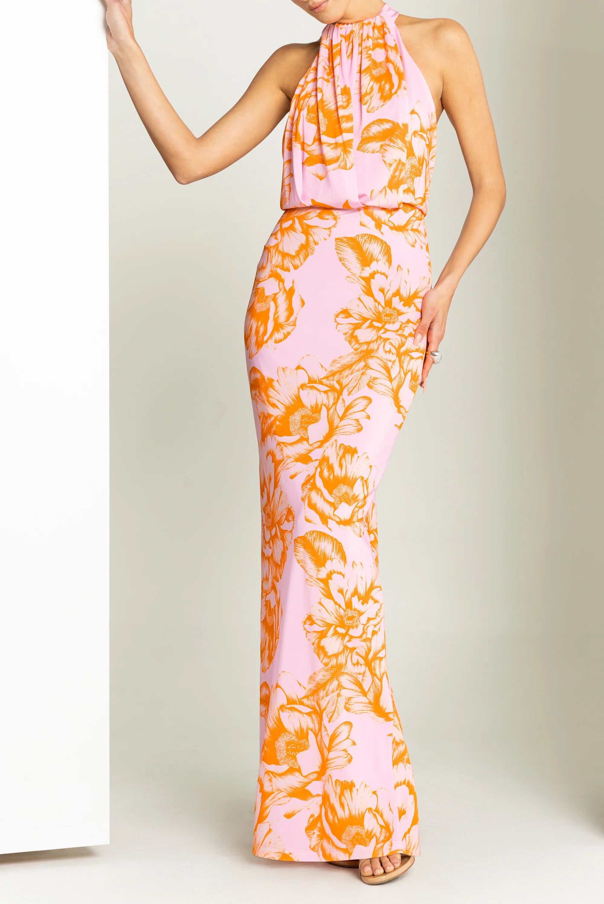 Woman wearing a pink and orange floral dress against a plain background