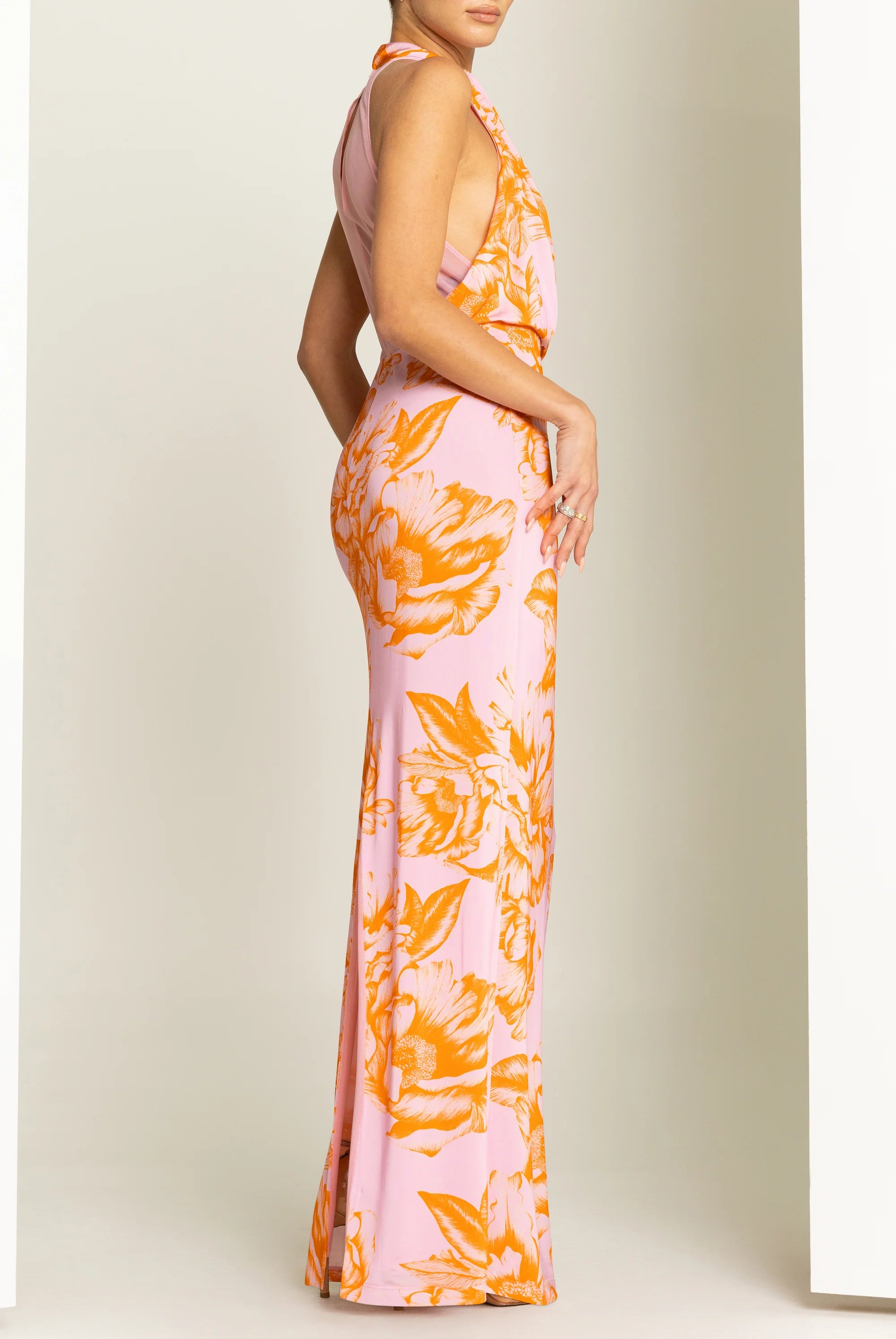 Woman wearing a pink and orange floral dress against a white background