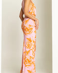 Woman wearing a pink and orange floral dress against a white background