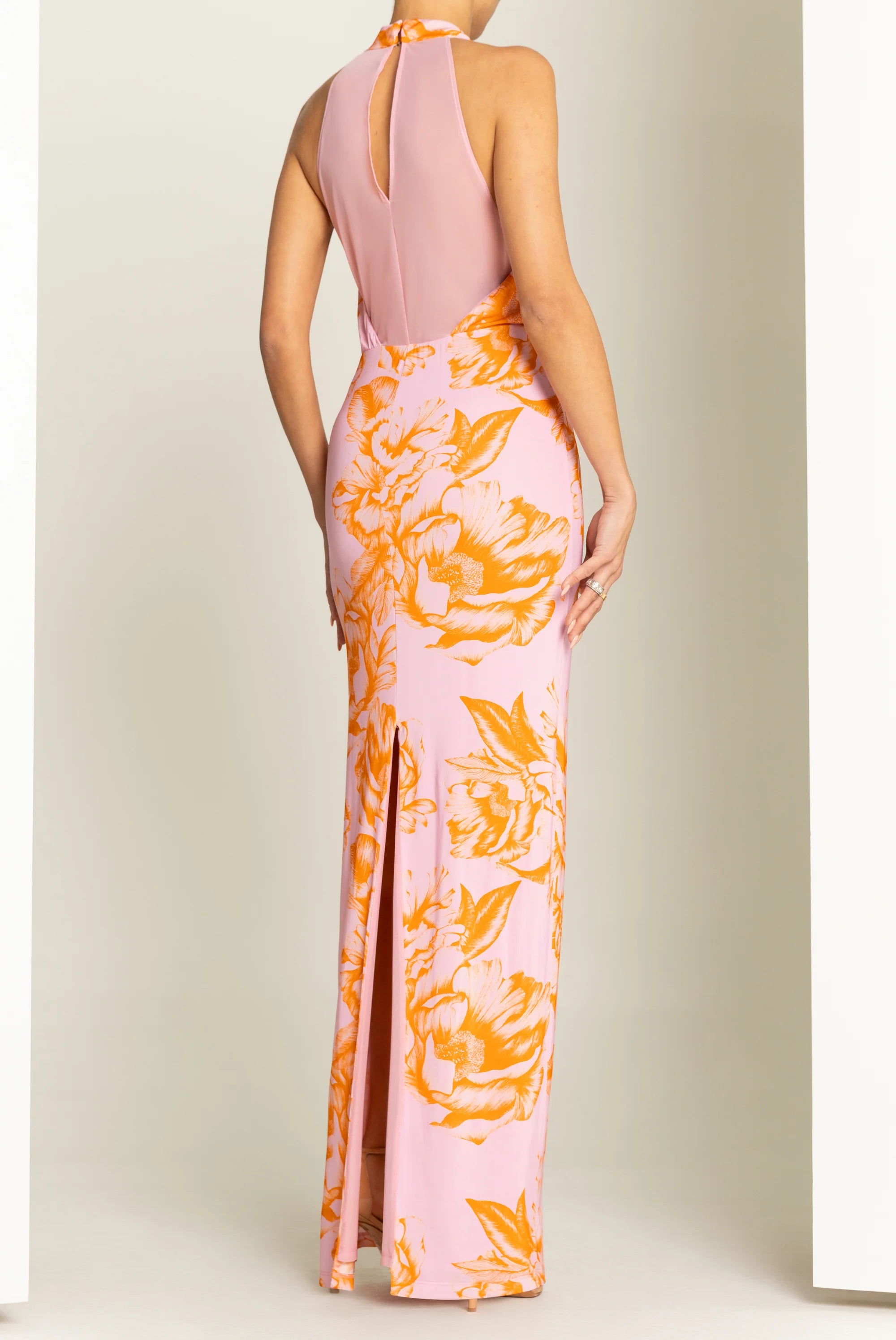 Pink and orange floral dress with a high slit on a plain background