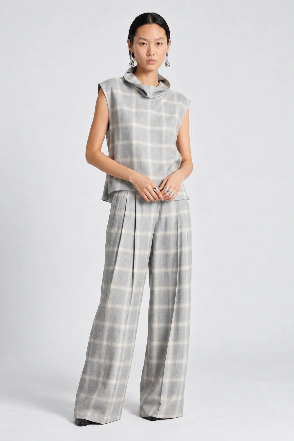 model wearing a grey and white plaid pant with a matching cowl neck sleeveless top 