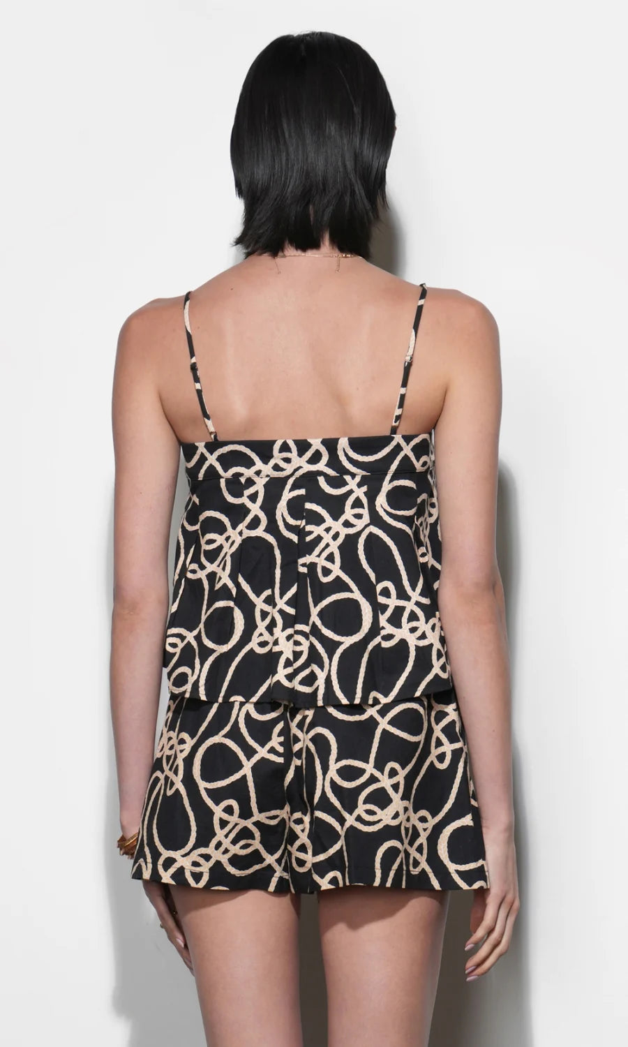 Woman wearing a black and beige patterned matching set against a white background