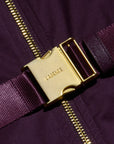 Close-up of a dark purple garment with a wide matching purple woven strap and a prominent gold-tone metal buckle engraved with the brand name LABERGE.