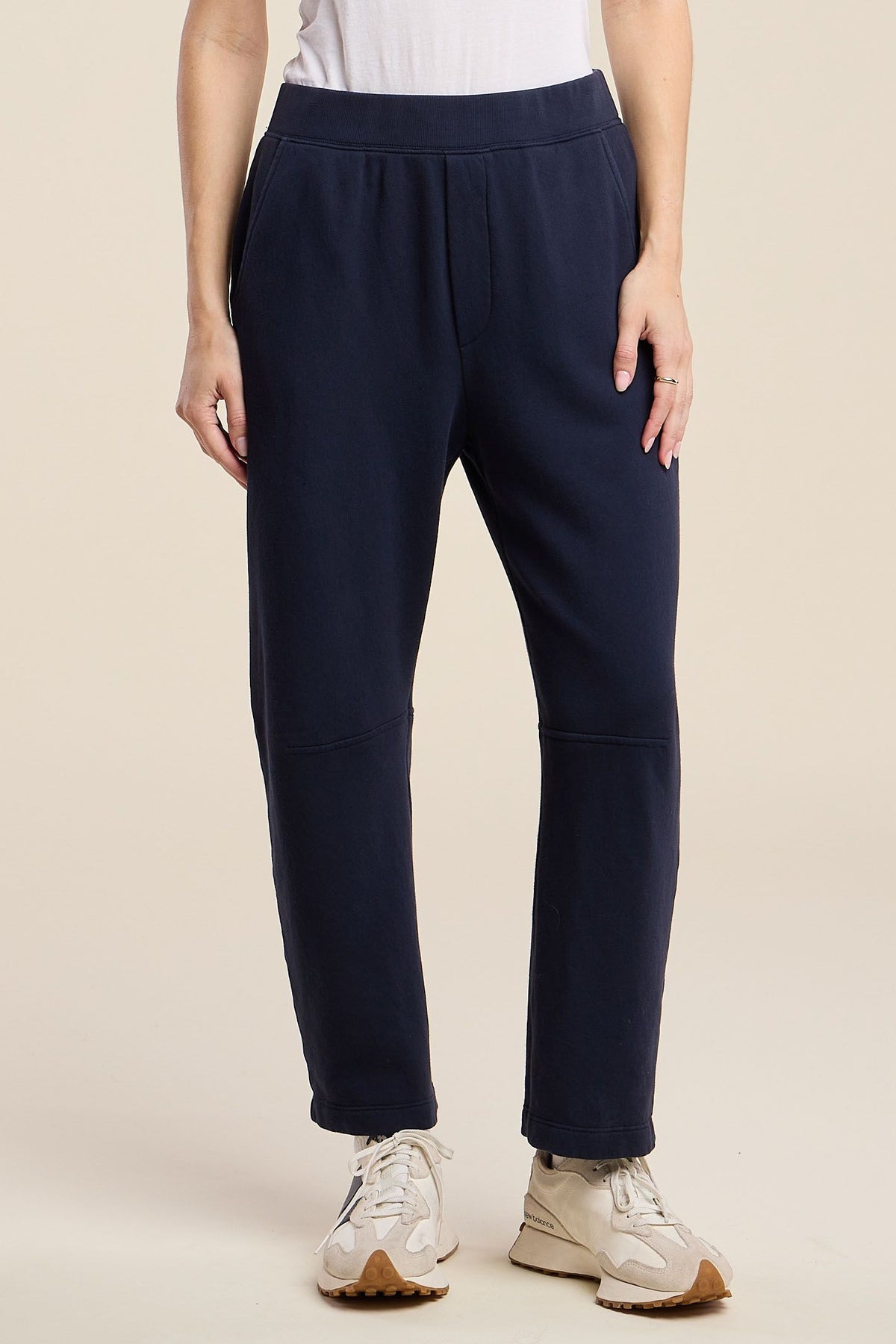 navy sweat pant on a model with sneakers and a white tee with a cream background