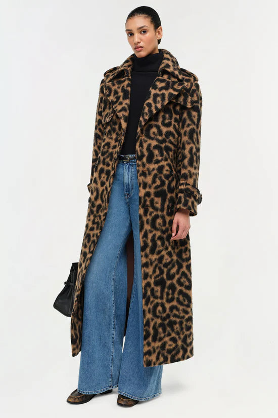 Woman wearing a leopard print coat with blue jeans on a white background