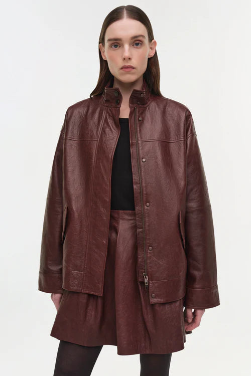 Woman wearing a brown leather jacket and skirt on a white background