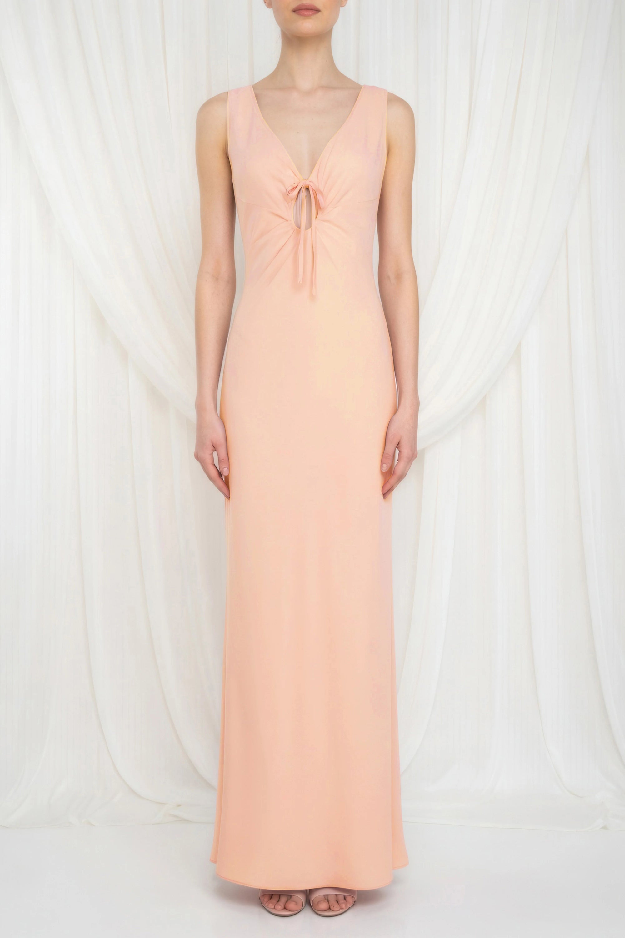 Woman wearing a peach-colored dress with a deep neckline on a white background