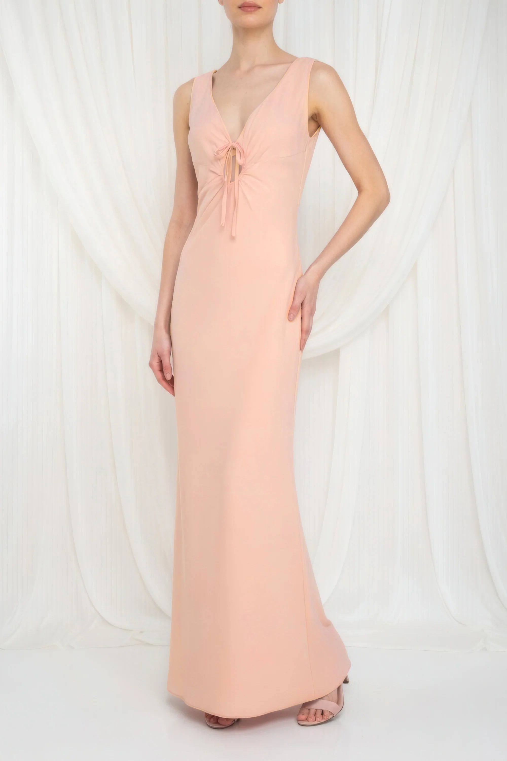 Woman wearing a long pink dress with a deep neckline on a white background