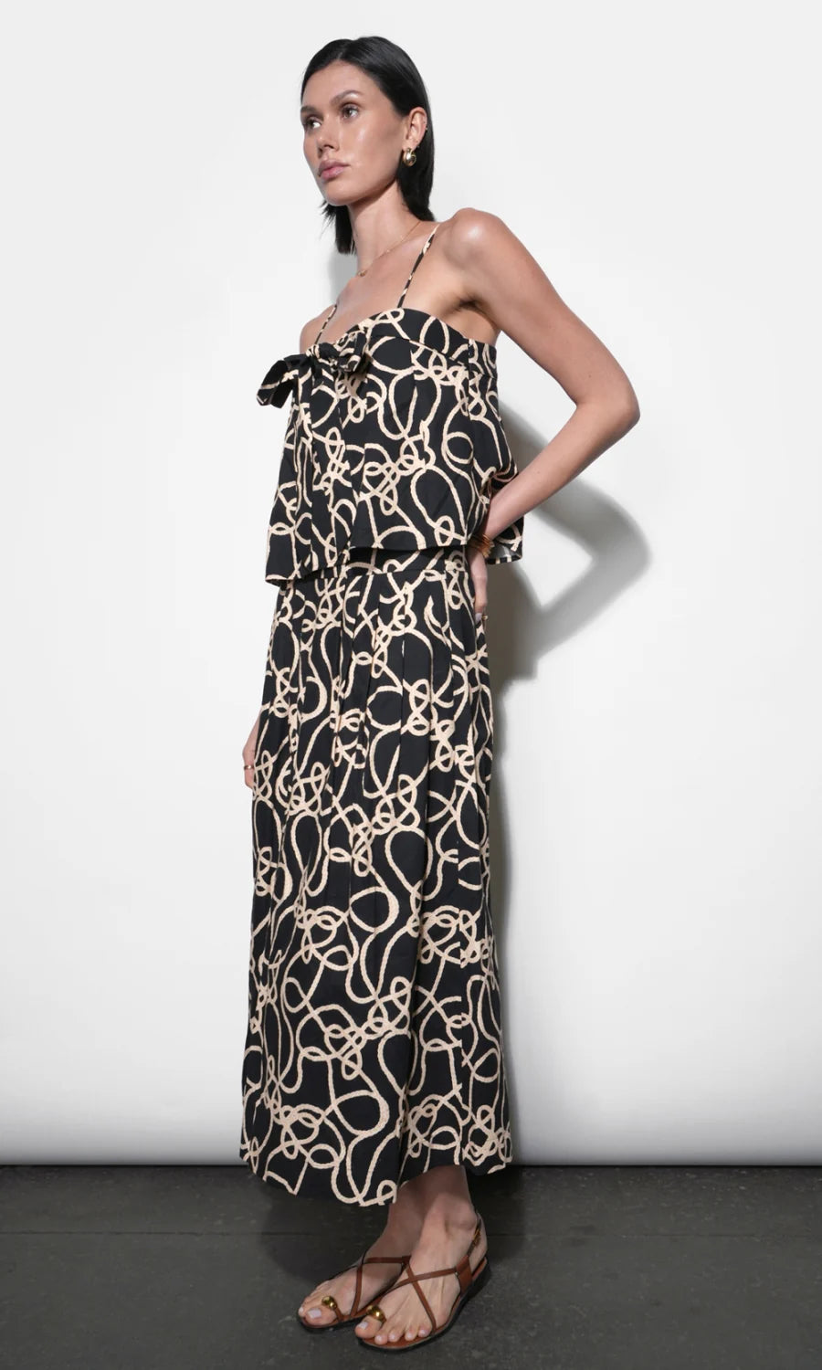 Woman wearing a black and beige patterned dress against a white background
