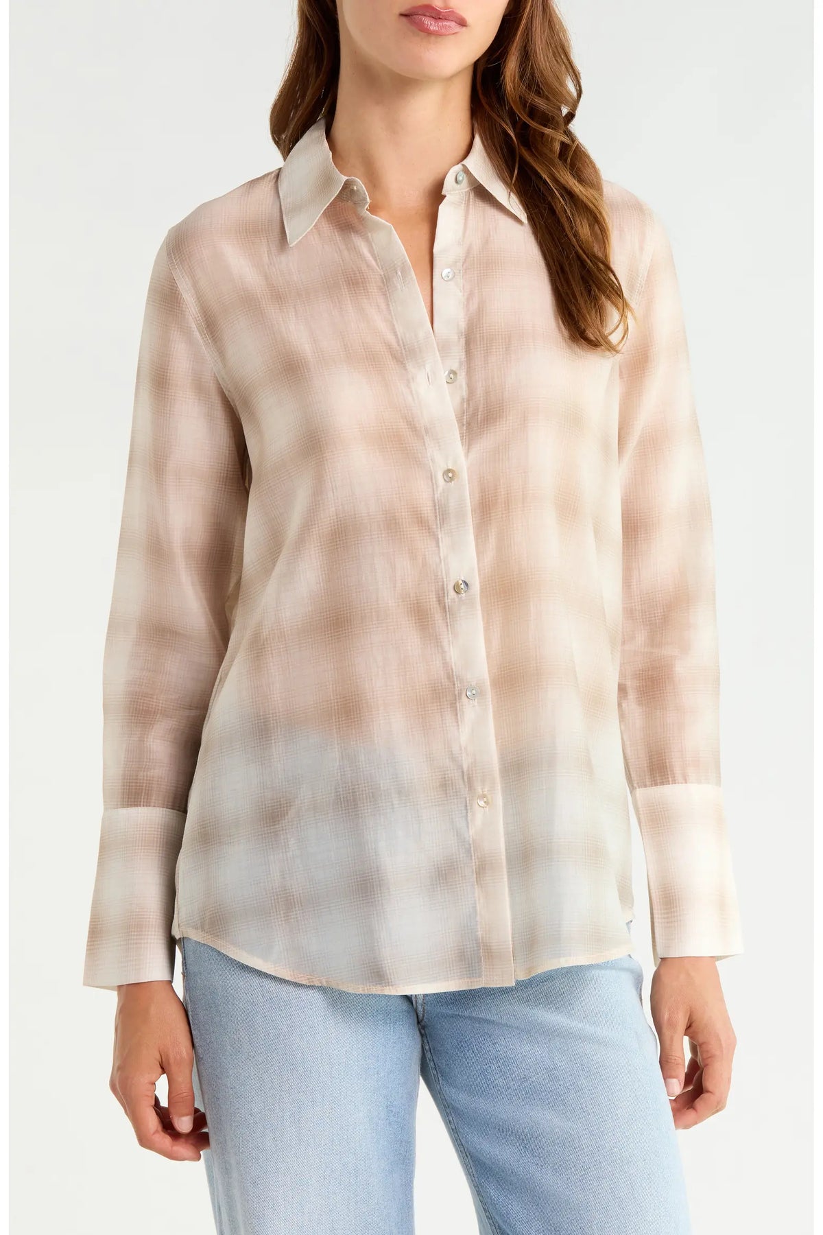 A woman wearing a long-sleeve button-up shirt with a soft beige and light brown plaid pattern, paired with light blue jeans, against a plain white background.