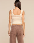 A woman shown from the back wearing a cream knit cropped tank top and brown wide-leg pants, against a solid beige studio background.