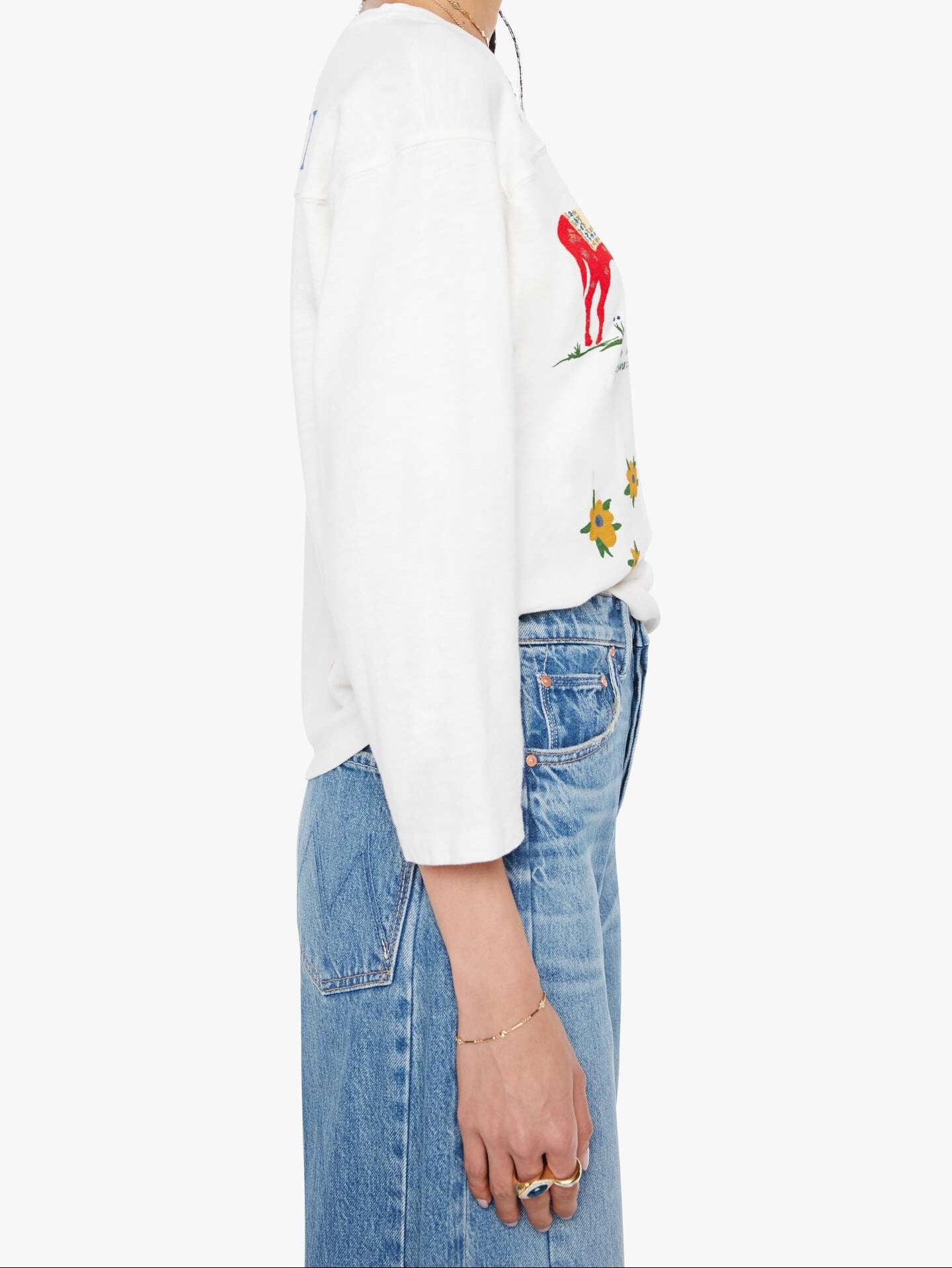 Person wearing a white sweatshirt with colorful graphics and blue jeans on a white background