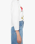 Person wearing a white sweatshirt with colorful graphics and blue jeans on a white background