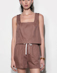 Woman wearing a brown sleeveless top and shorts set against a white background
