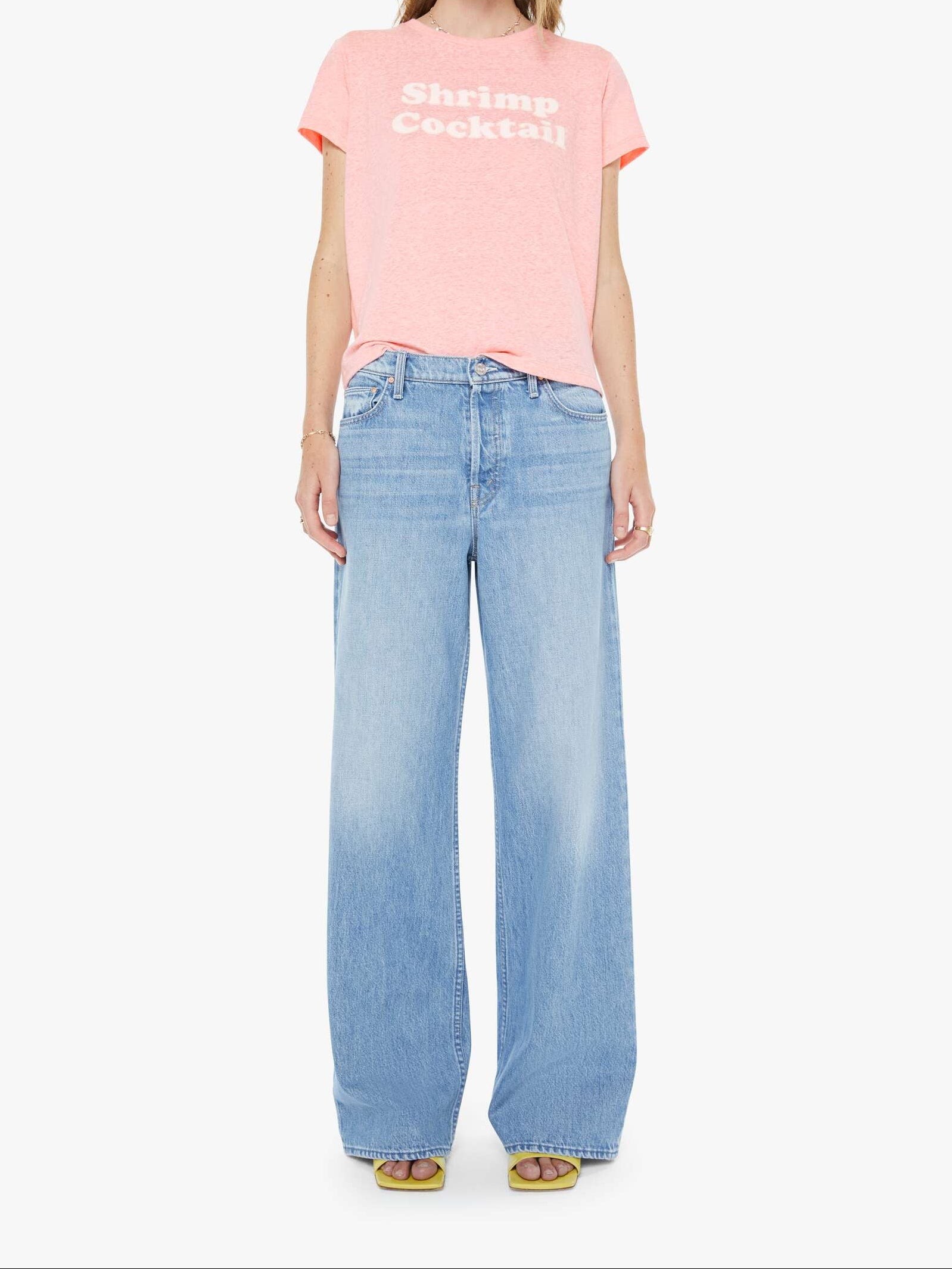 Woman wearing a pink t-shirt with text and light blue jeans on a white background