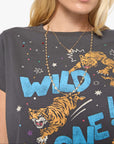 A close-up of a model wearing a dark gray graphic t-shirt with a tiger and the words 'WILD ONE!' in blue and orange, accessorized with layered gold necklaces.