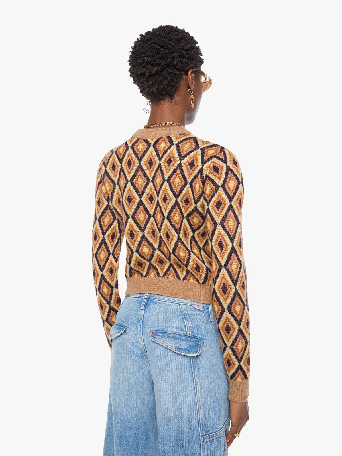 Person wearing a patterned sweater and jeans on a white background