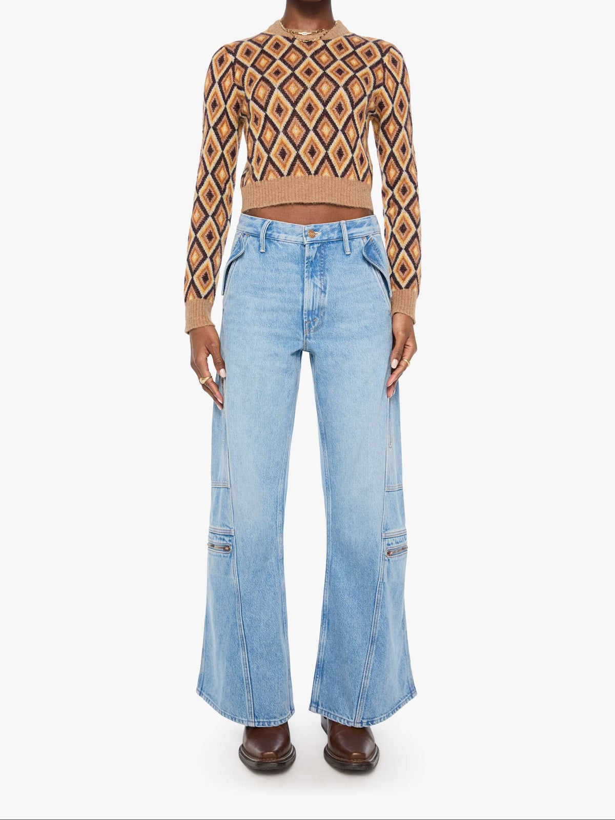 A model wearing a brown and beige patterned long-sleeve crop top paired with light blue wide-leg denim jeans and dark brown shoes, standing against a plain white background.