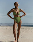 model wearing green bikini in beach setting