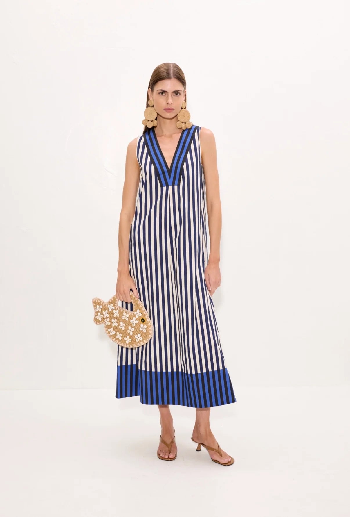 model wearing a stripe dress holding a fish bag on a white background