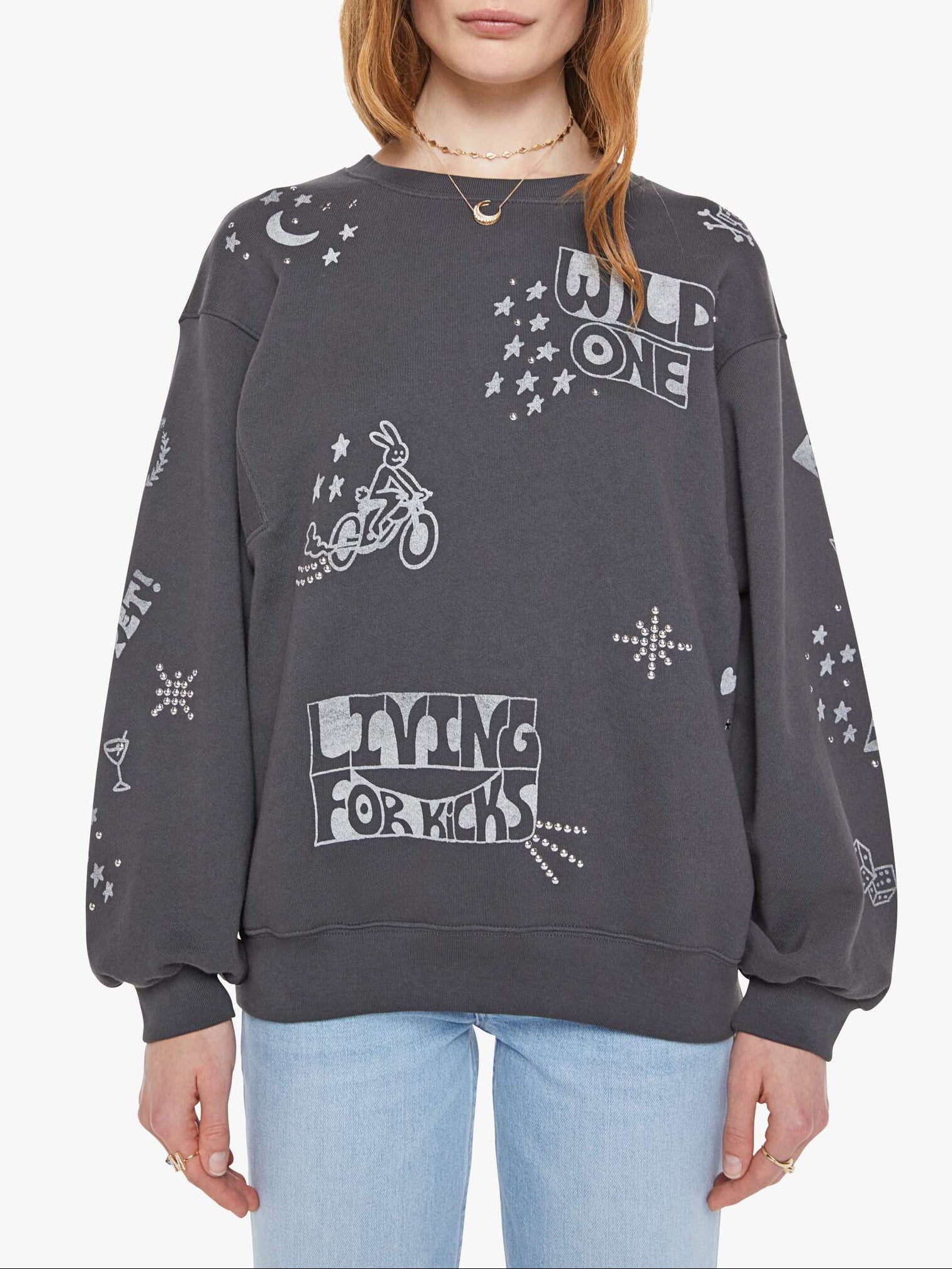 Woman wearing a dark gray sweatshirt with graphic designs on a white background