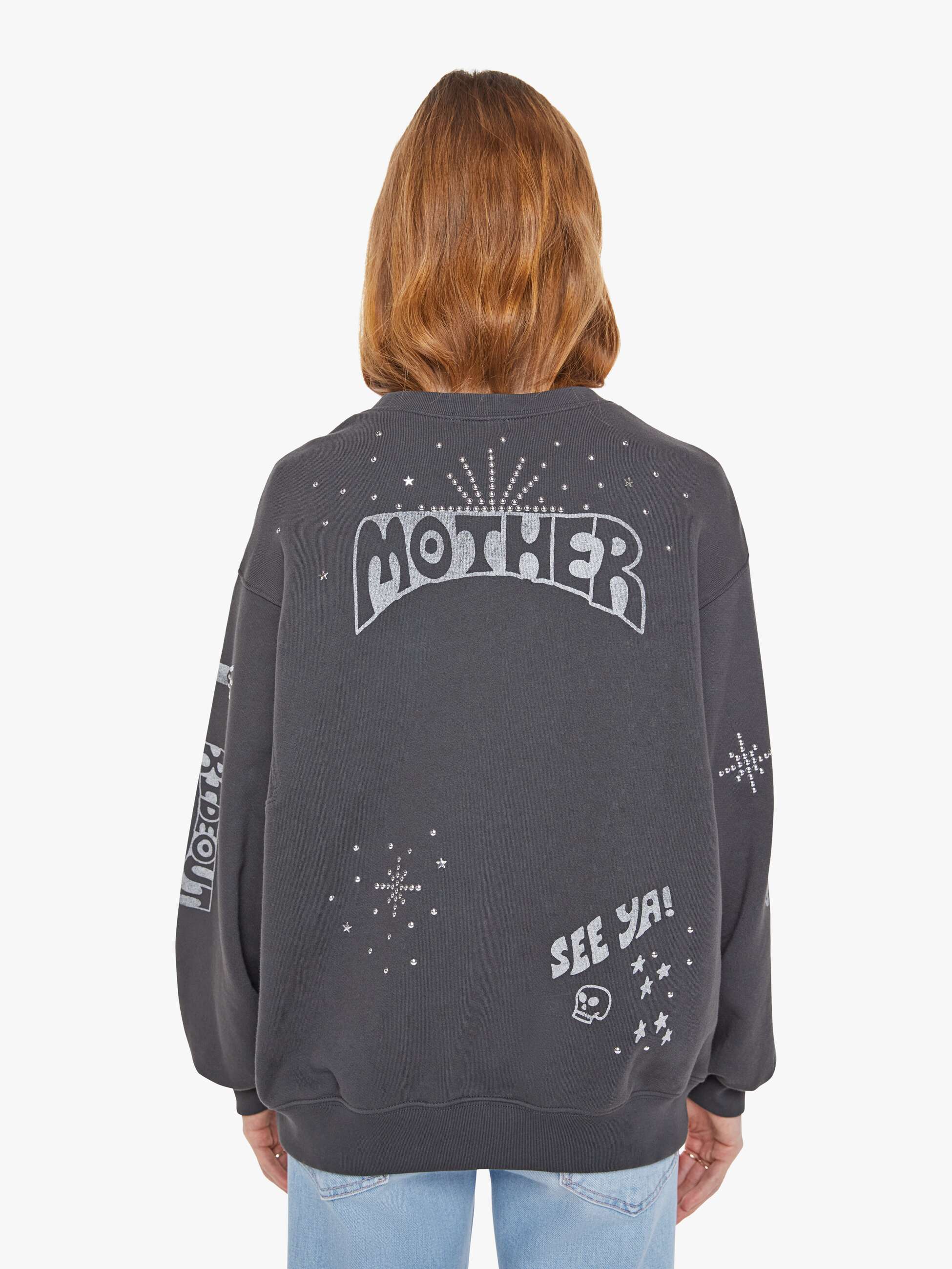 Person wearing a dark gray sweatshirt with text and graphics on the back, standing against a white background. back view