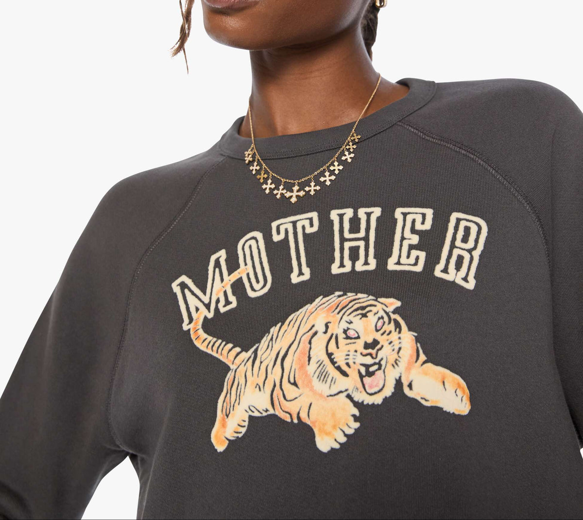 Woman wearing a dark gray sweatshirt with a tiger graphic and 'MOTHER' text on a white background