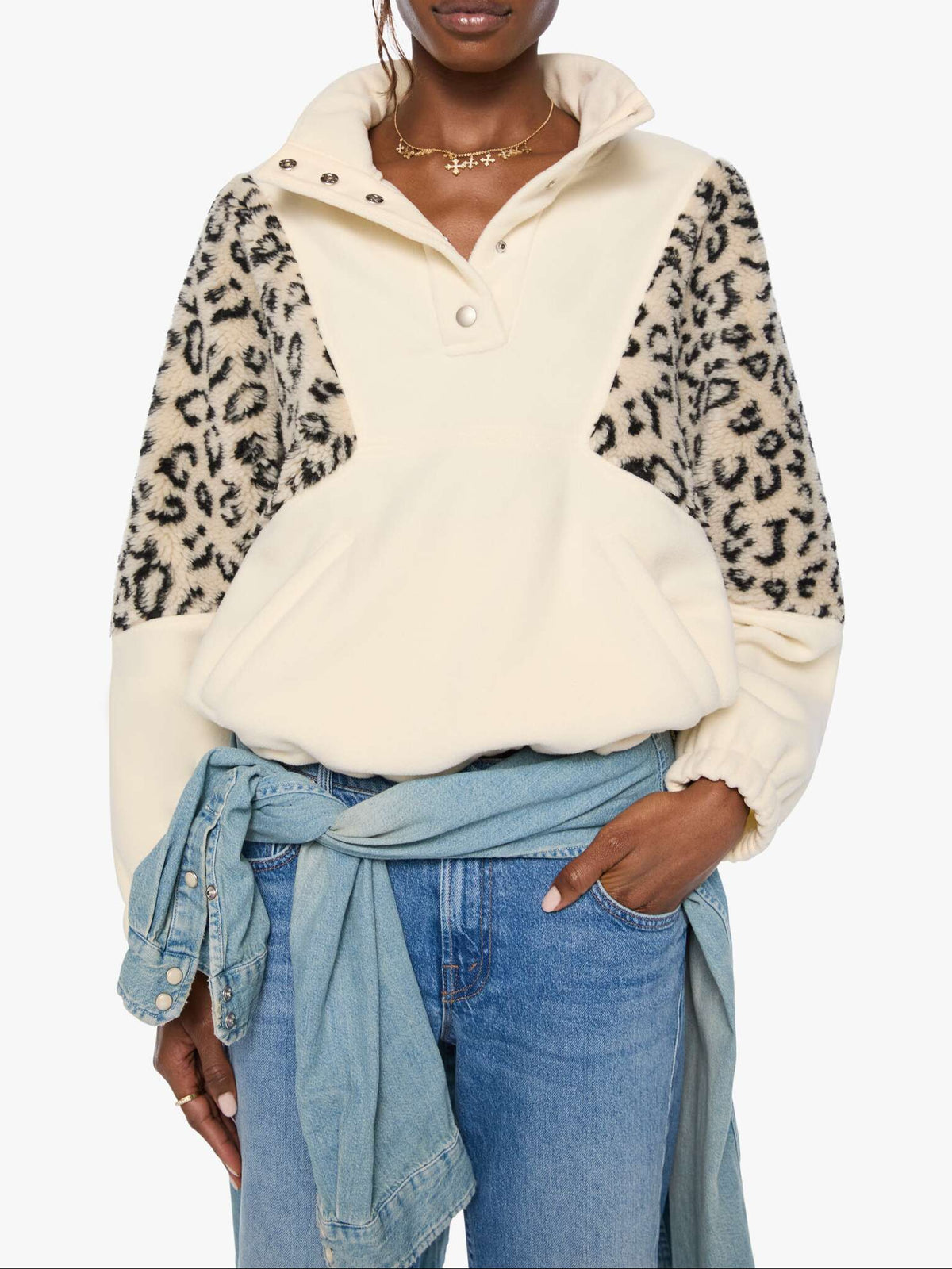 Woman wearing a cream-colored shirt with leopard print sleeves on a white background