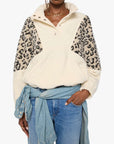 Woman wearing a cream-colored shirt with leopard print sleeves on a white background