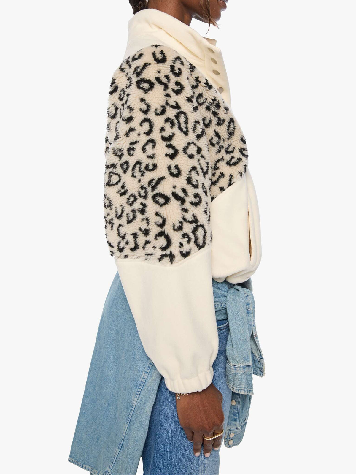 Person wearing a leopard print sweater over a cream turtleneck with a denim jacket on a white background