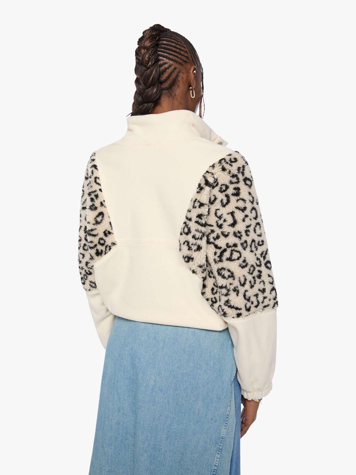 Person wearing a white fleece vest with leopard print sleeves on a white background